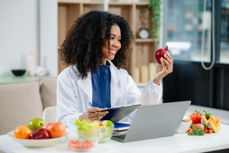 Nutricionista sorridente segura alimento fresco enquanto orienta sobre dieta equilibrada, destacando a importância da saúde intestinal para o bem-estar.